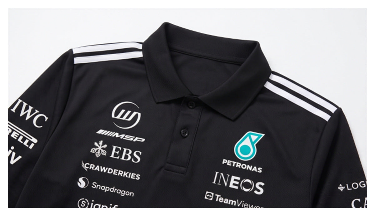 Close-up of the black polo front showing its collar, white shoulder stripes, buttons, and printed sponsor logos.