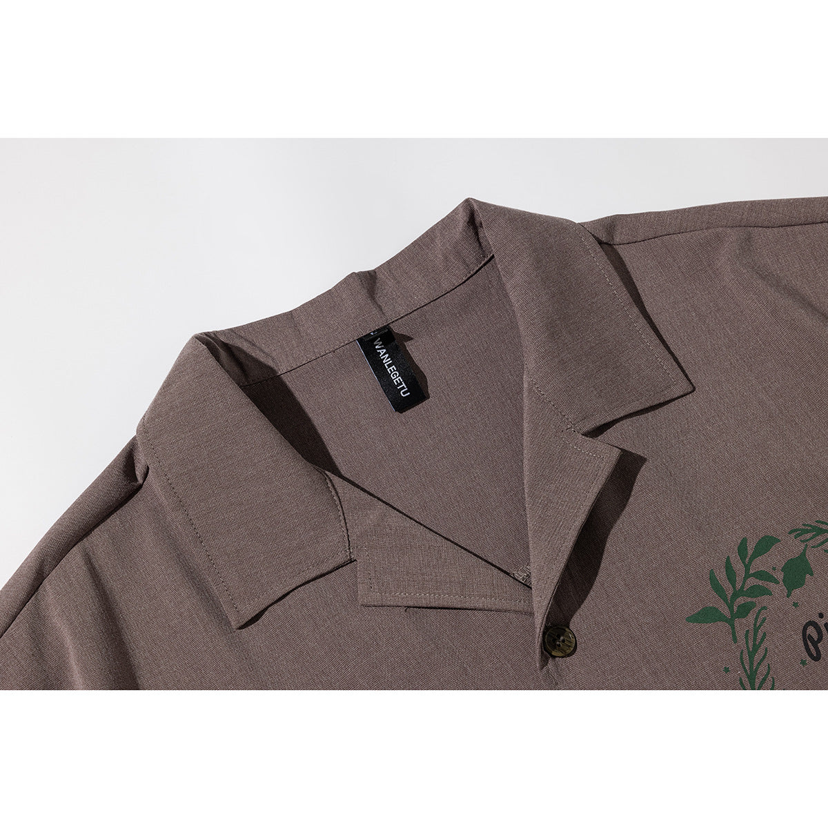 Close-up of a brown short-sleeve shirt's notched collar, button, and sewn neck label.