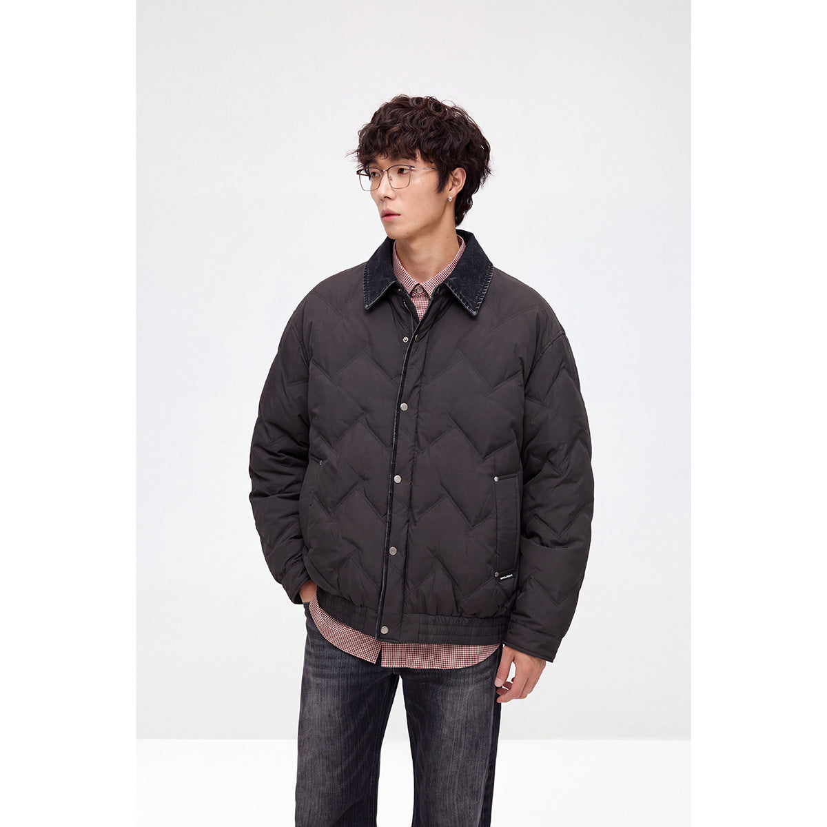Model wearing a black chevron-quilted jacket with a dark contrast collar, snap front, and ribbed hem.