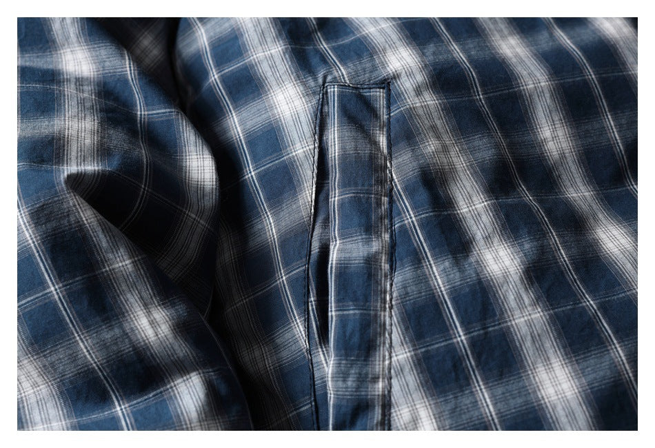Close-up of a narrow vertical pocket opening on blue-gray plaid fabric.