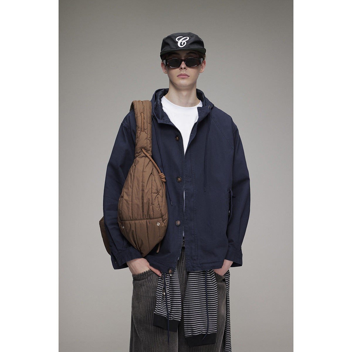Front view of a model wearing a navy hooded button-front jacket over a white T-shirt.