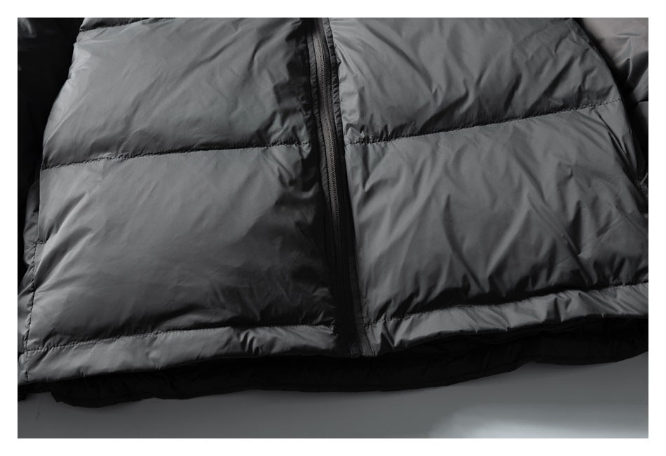 Close-up of a dark gray quilted puffer jacket with horizontal stitching and a central black zipper.