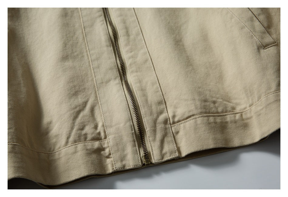 Close-up of a beige jacket hem with a centered metal zipper and stitched seams.