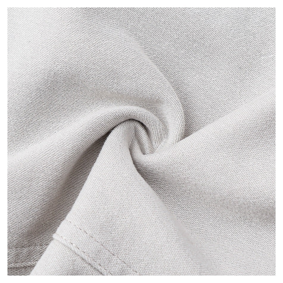 Macro close-up of light gray garment fabric gathered into a fold, showing its surface texture and stitching.