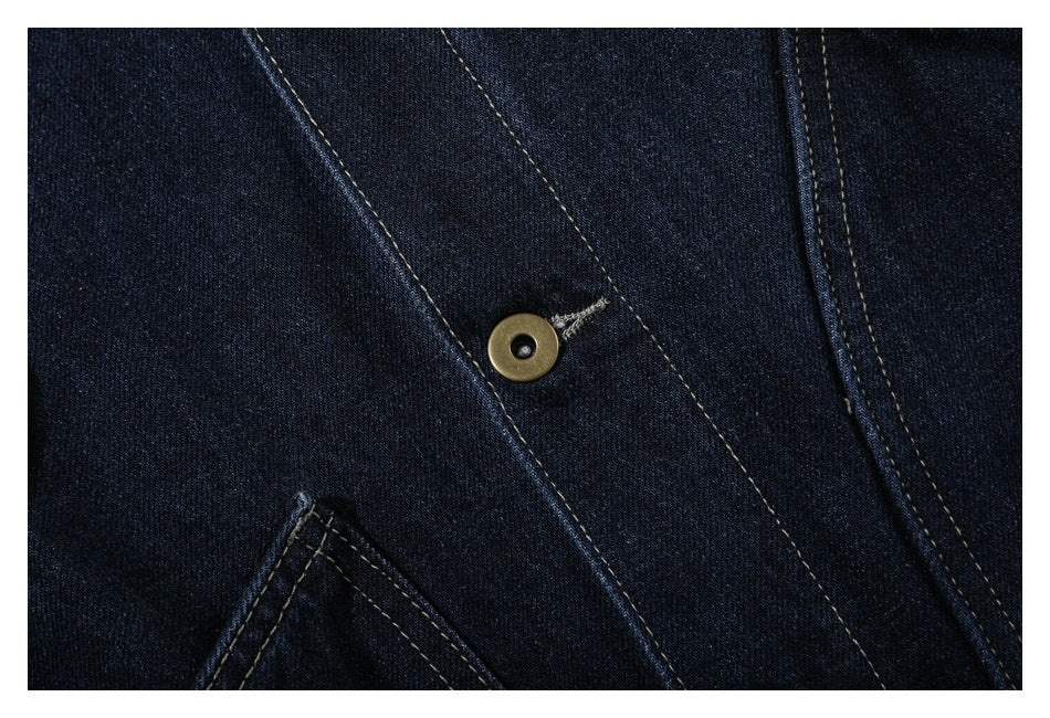 Close-up of a brass-tone button and contrast stitching on dark indigo denim.