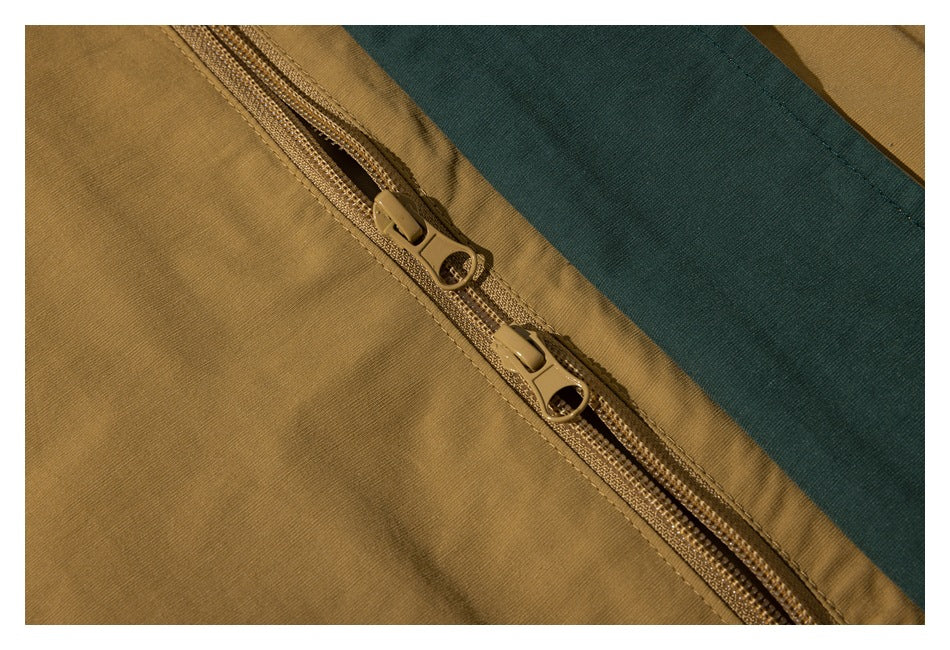 Close-up of a two-way zipper beside a dark teal panel on a mustard-brown garment.