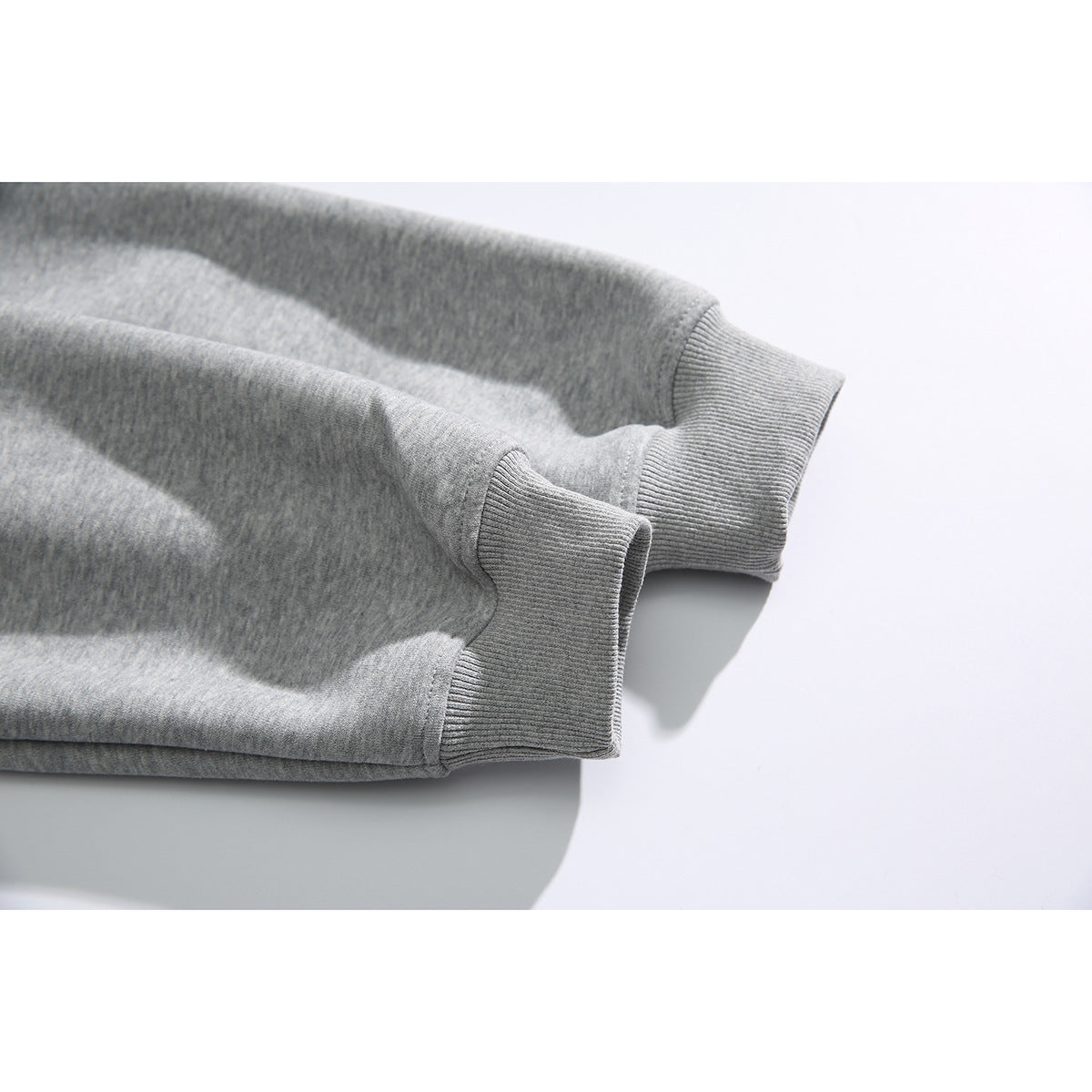 Close-up of the heather gray hoodie’s sleeve ends, showing wide ribbed cuffs.