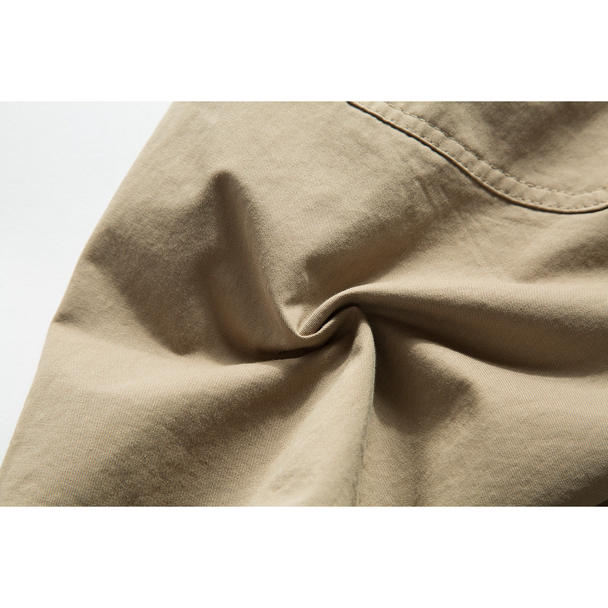 Close-up of tan shorts fabric folds and a curved stitched seam.