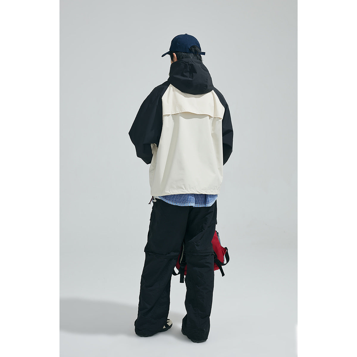 Back view of a model wearing a cream jacket with black sleeves and hood.