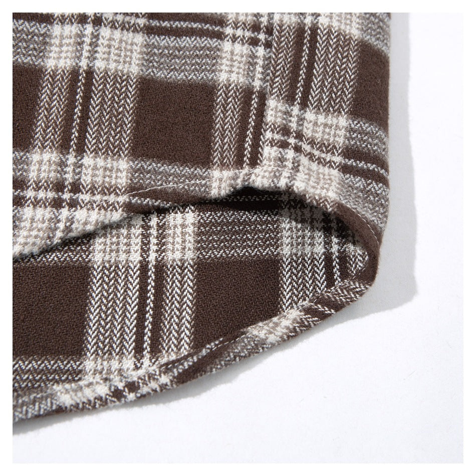 Close-up showing the stitched hem of a brown and cream plaid shirt.