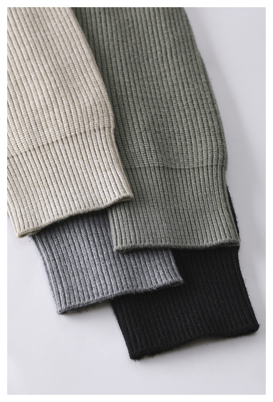 Close-up of ribbed sweater cuffs in beige, olive, gray, and black, arranged together.