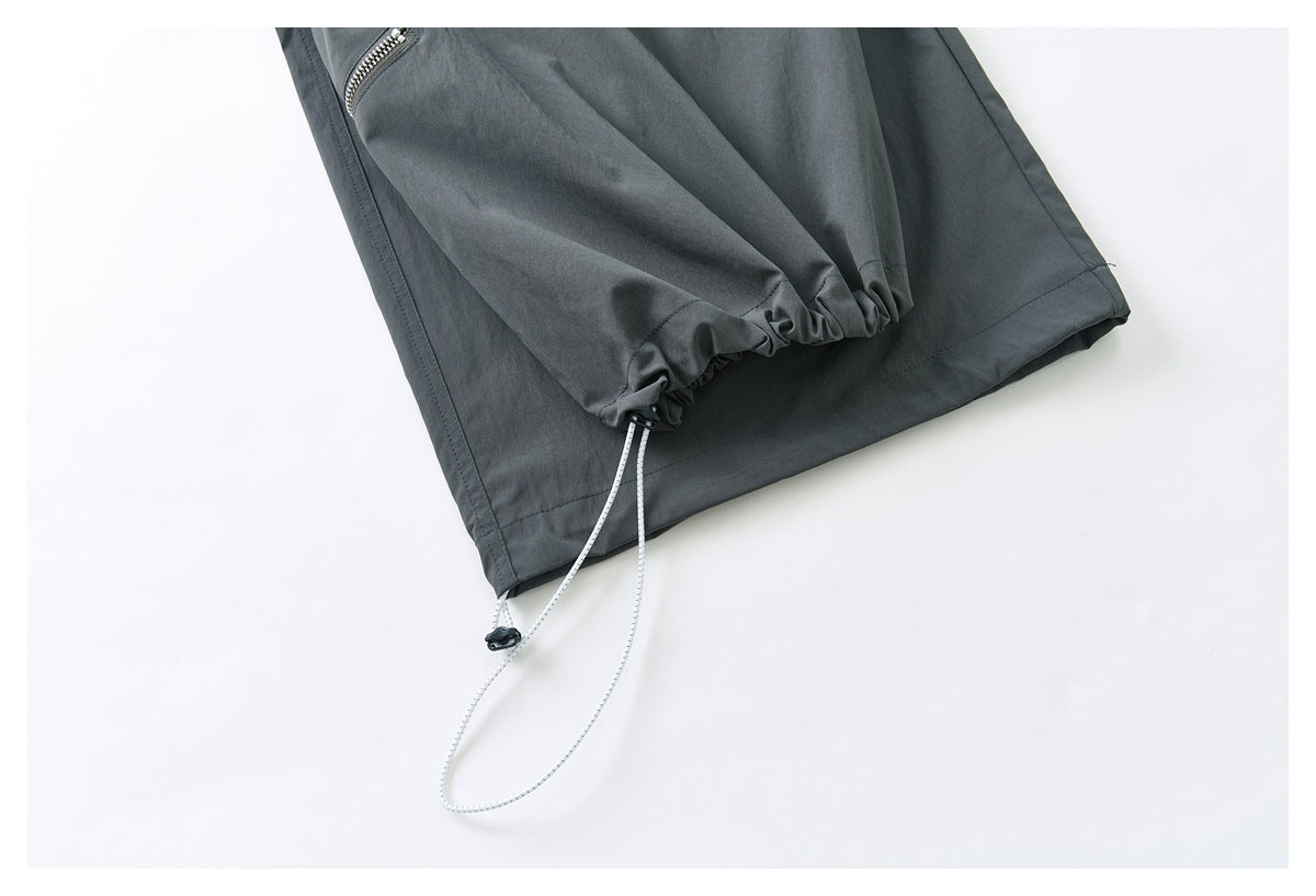 Close-up of a charcoal-gray trouser hem with gathered elastic and an adjustable drawcord.
