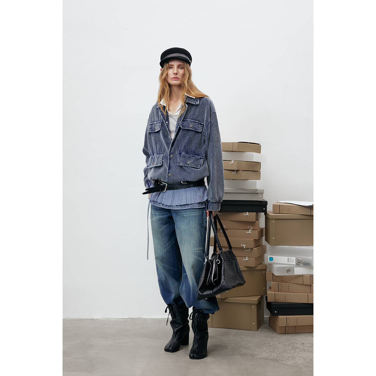 Model wearing a blue ribbed button-front jacket with four flap pockets, wide jeans, a pleated top, and black boots.