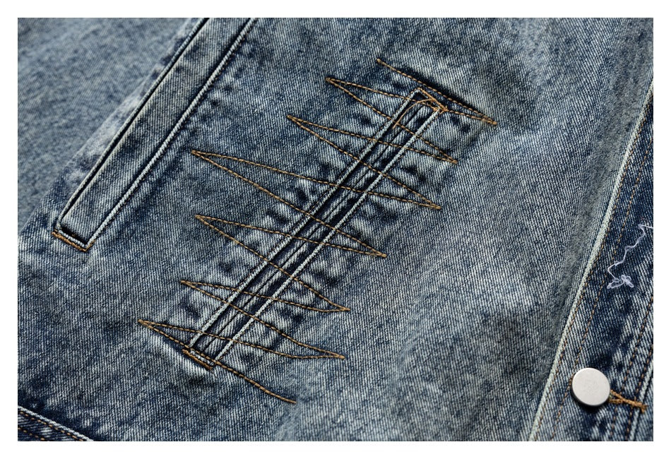 Close-up of a blue denim jacket panel with bold crisscross stitching and a metal snap.