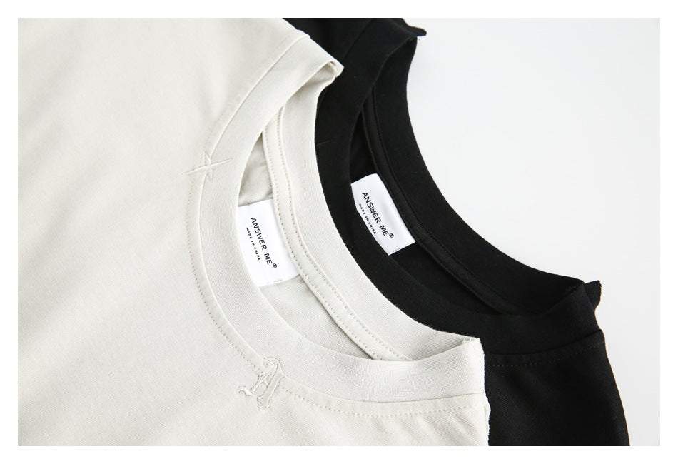 Close-up of off-white and black top necklines, showing collar stitching, small embroidery, and brand labels.