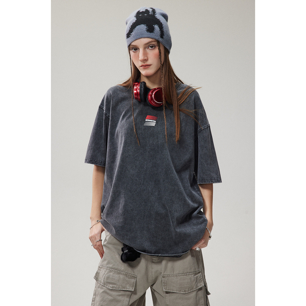 Close view of a model wearing an oversized washed charcoal T-shirt with a small striped chest graphic.