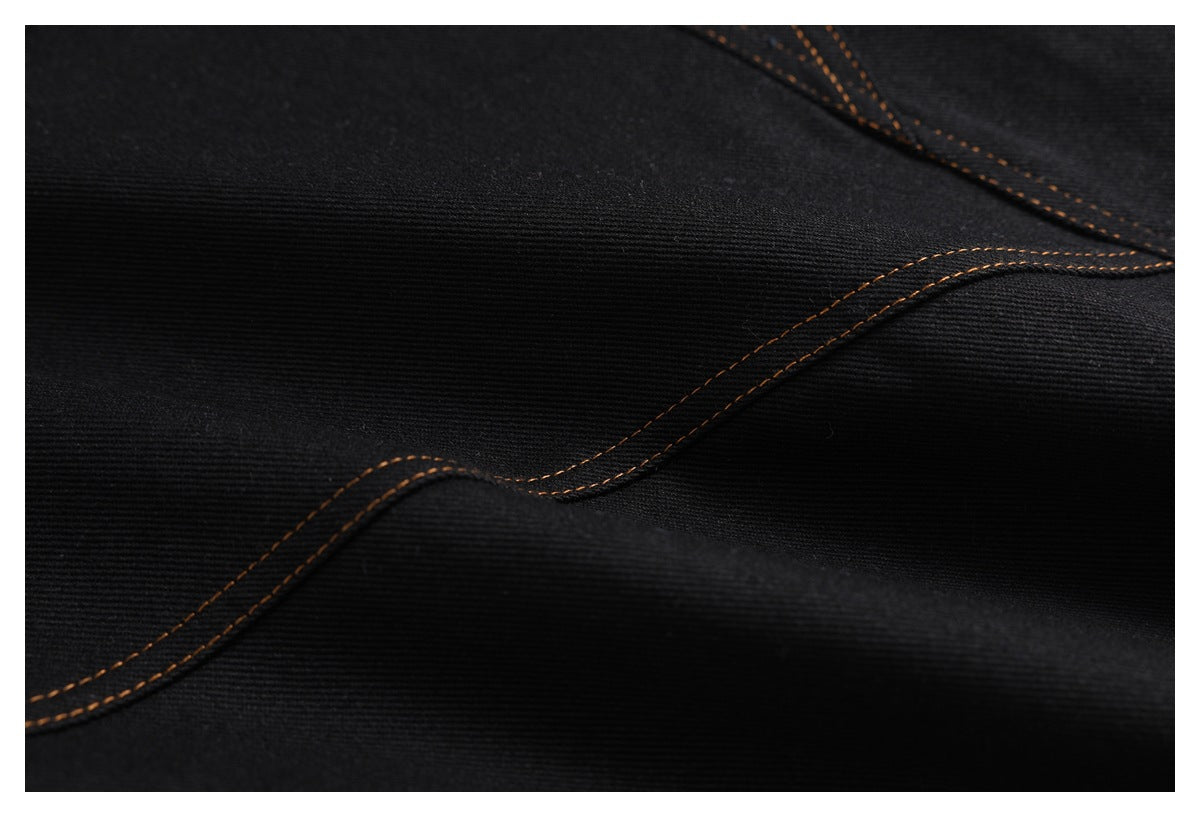Close-up of black denim with curved, parallel brown stitching along a seam.