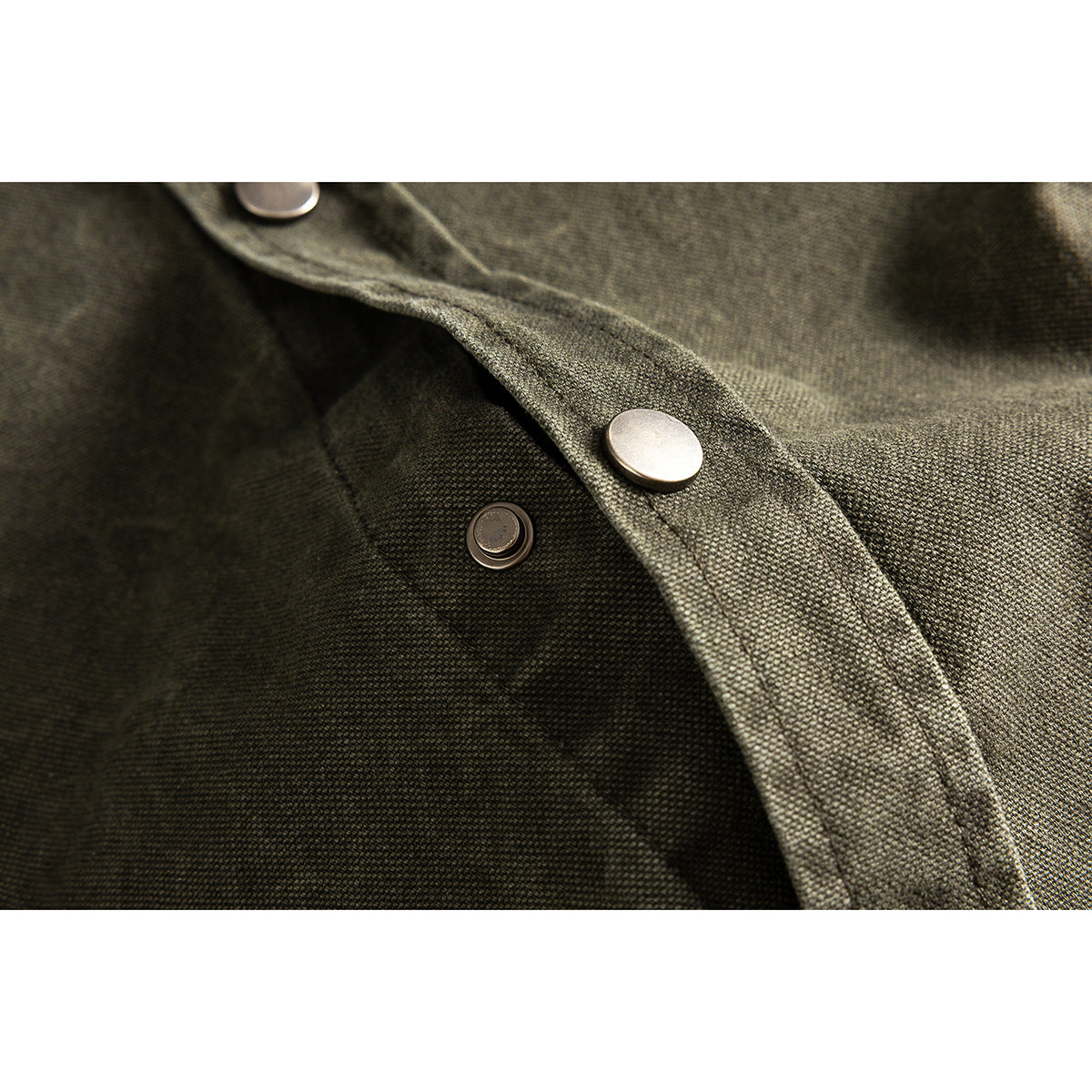 Close-up of an olive-gray shirt's snap-button placket and textured fabric.