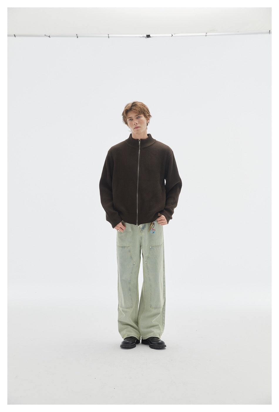 Model facing front in brown ribbed zip-front sweater with light green wide-leg pants