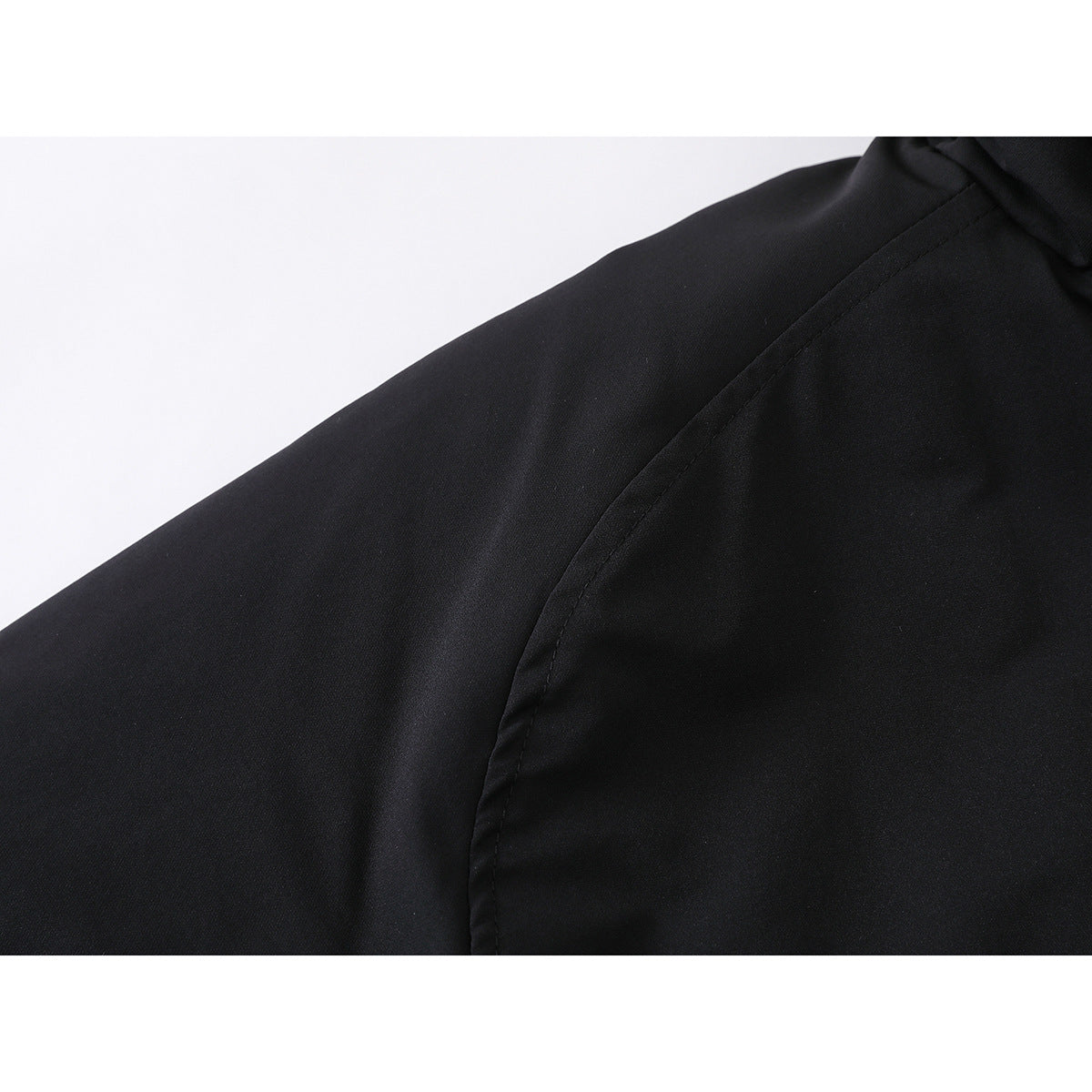 Close-up of a black jacket’s shoulder and sleeve seam.