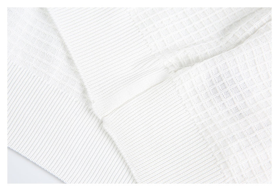 Close-up of white knit fabric with ribbed trim meeting a textured panel at a seam.