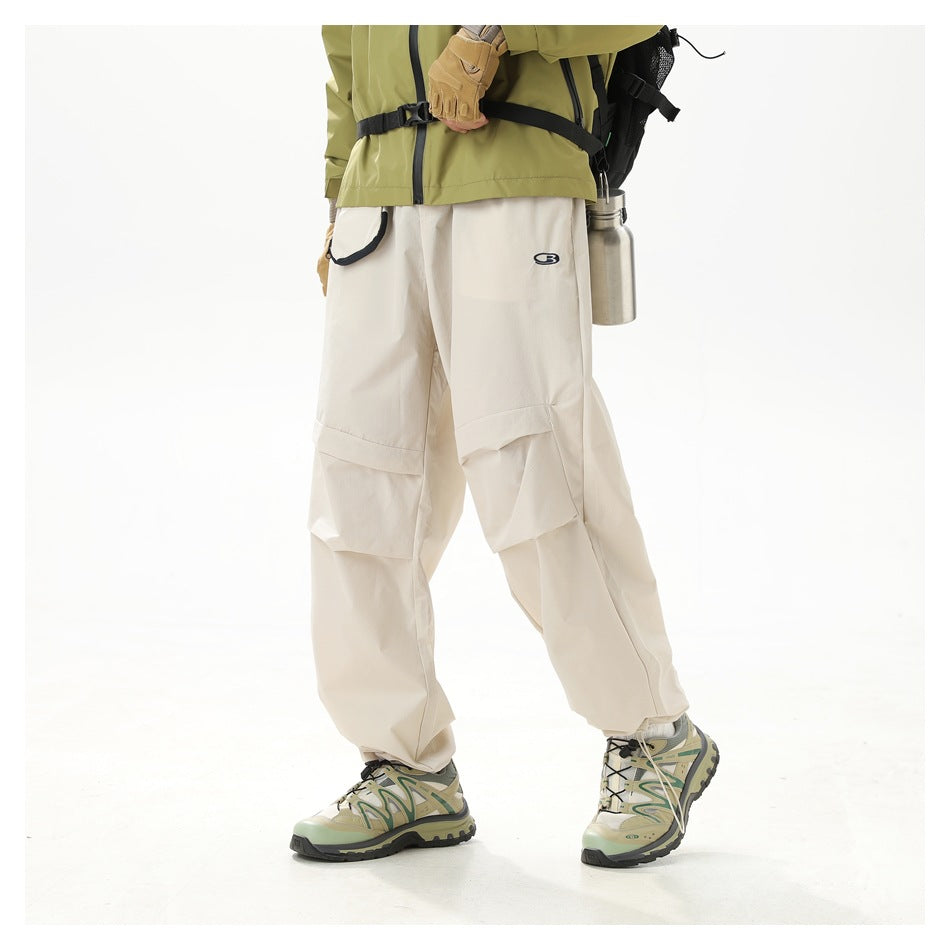 Side view of a model wearing loose ivory trousers with layered knee panels and a small dark emblem.