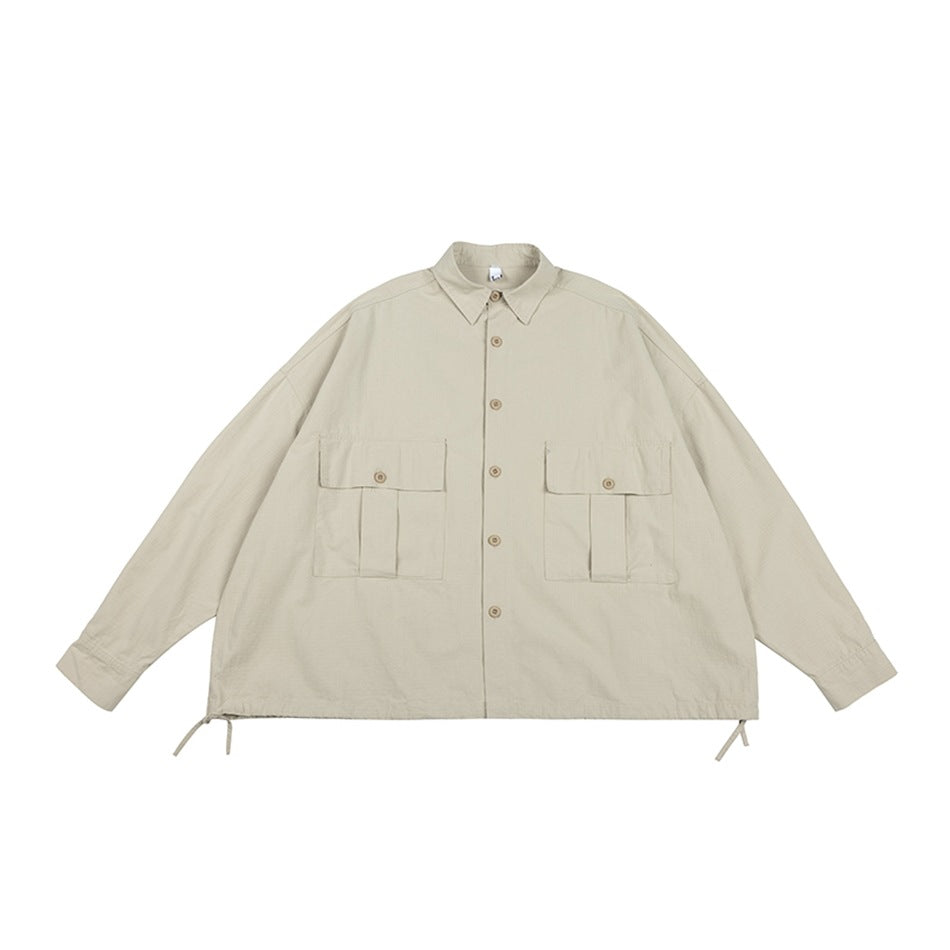 Light khaki button-front shirt-jacket flat lay with two flap chest pockets and side hem drawstring ties