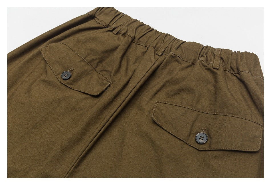 Rear view of brown pants showing an elastic waistband and two button-flap back pockets.