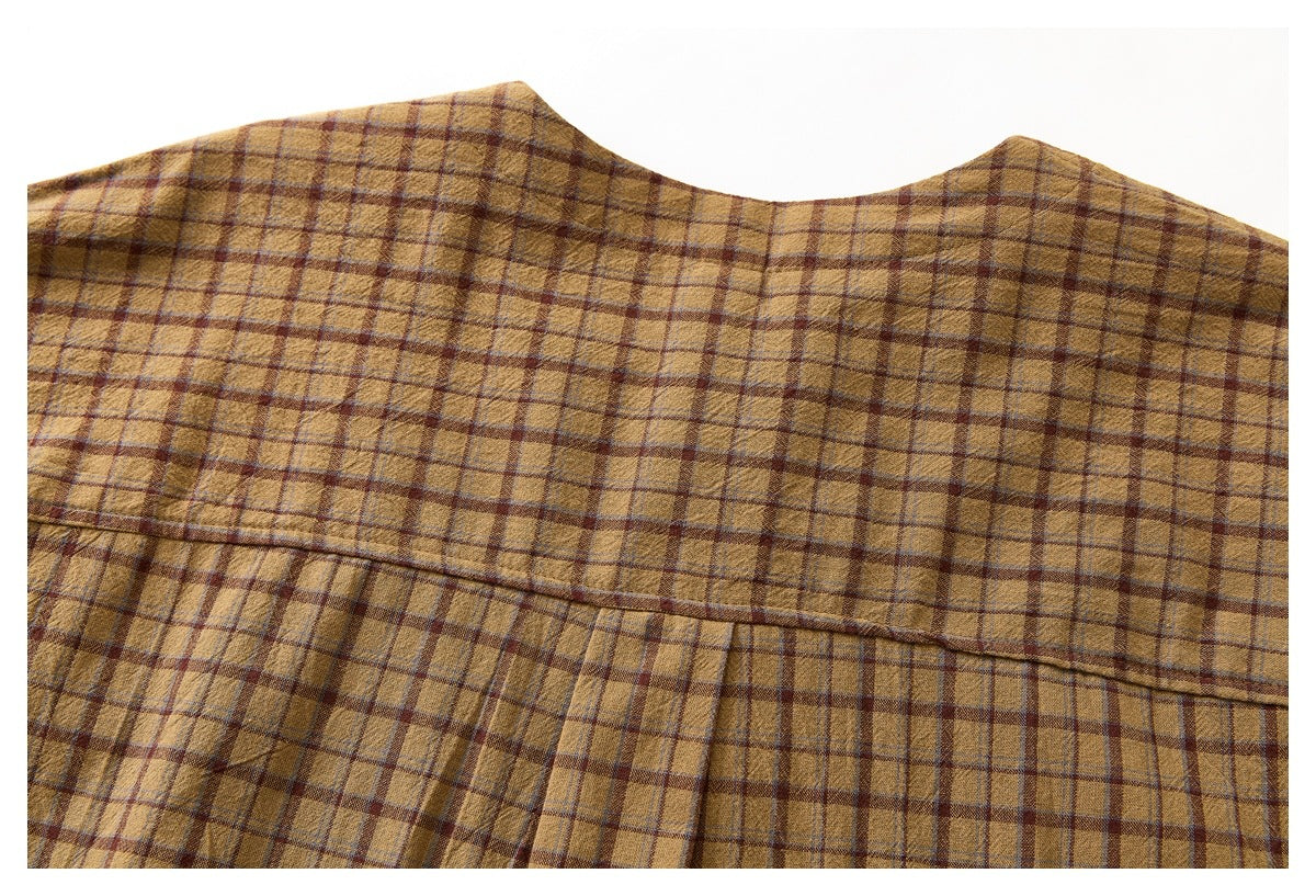 Close-up of the back yoke and shoulder seams on a mustard-brown plaid shirt.