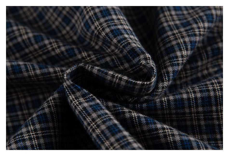 Macro view of the dark blue, beige, and black plaid fabric gathered into folds.