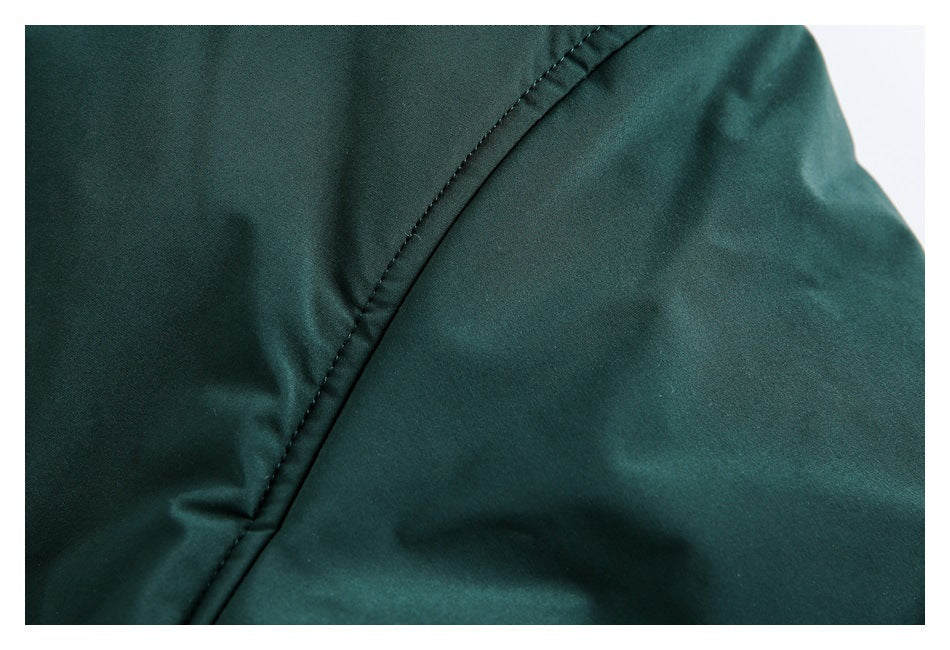 Close-up of a curved stitched seam on dark green garment fabric.