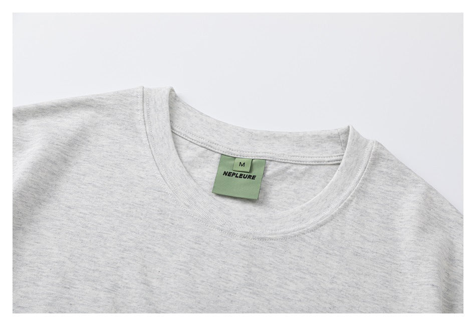 Close-up of the light gray heather T-shirt's crew neckline and green NEPLEURE size M label.