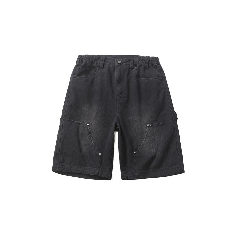 Front flat lay of black washed knee-length carpenter shorts with rivets and frayed diagonal seams