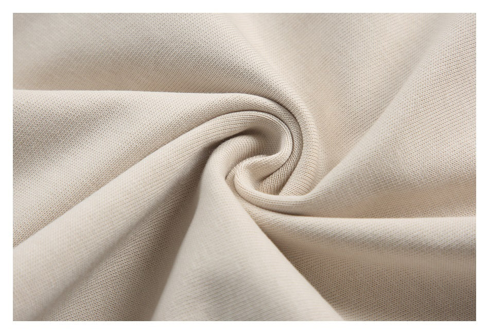 Close-up of light beige fabric gathered into a swirl, showing its fine knit texture.