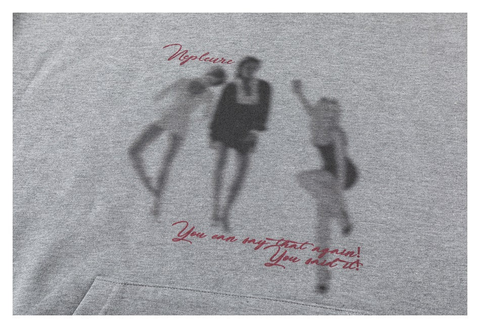 Close-up of a gray sweatshirt with a blurred silhouette graphic and red cursive lettering.
