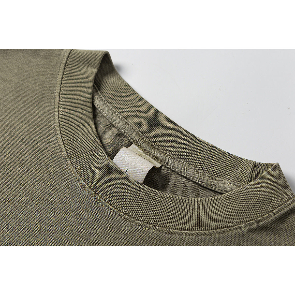 Close-up of an olive-gray T-shirt's ribbed crew neckline and inner collar stitching.