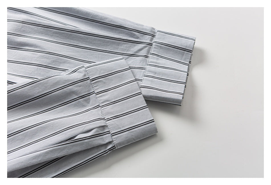 Close-up of two long sleeve cuffs on a white shirt with fine black stripes and wider black lines.