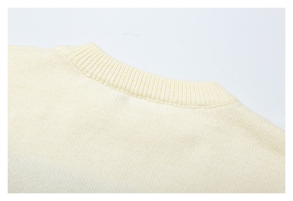 Close-up of the ribbed neckline and plain back of a cream knit sweater.
