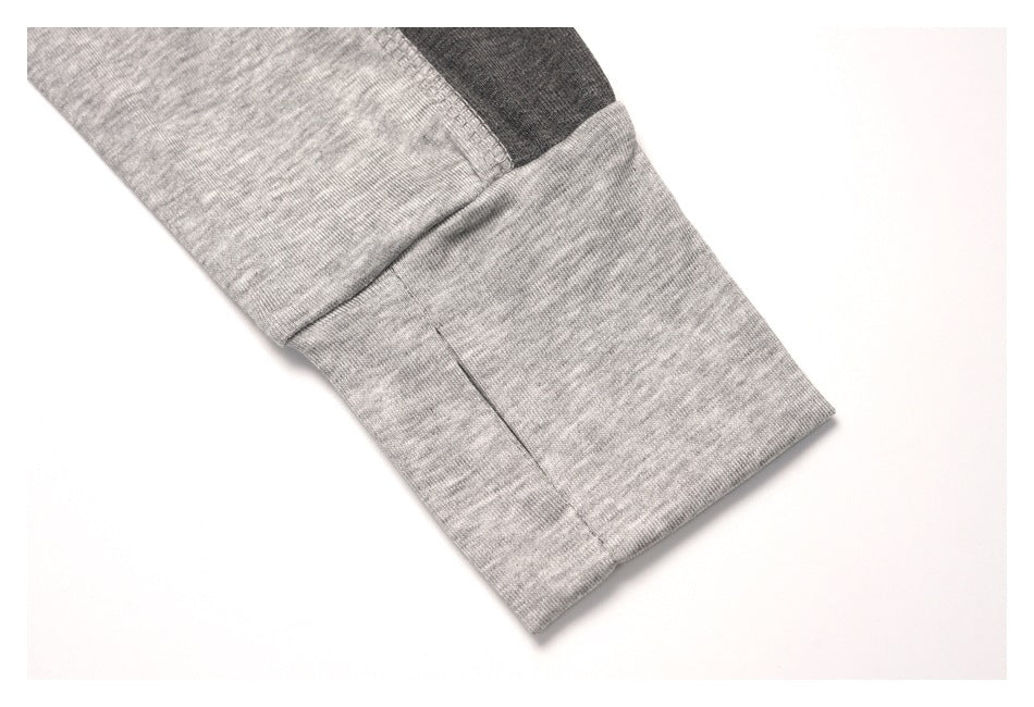 Close-up of a wide light gray heather sleeve cuff with a dark contrast panel above it.