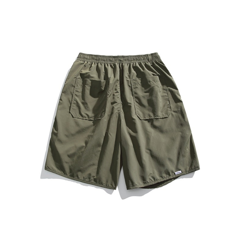Olive green shorts shown from the back, with an elastic waistband and two large patch pockets.