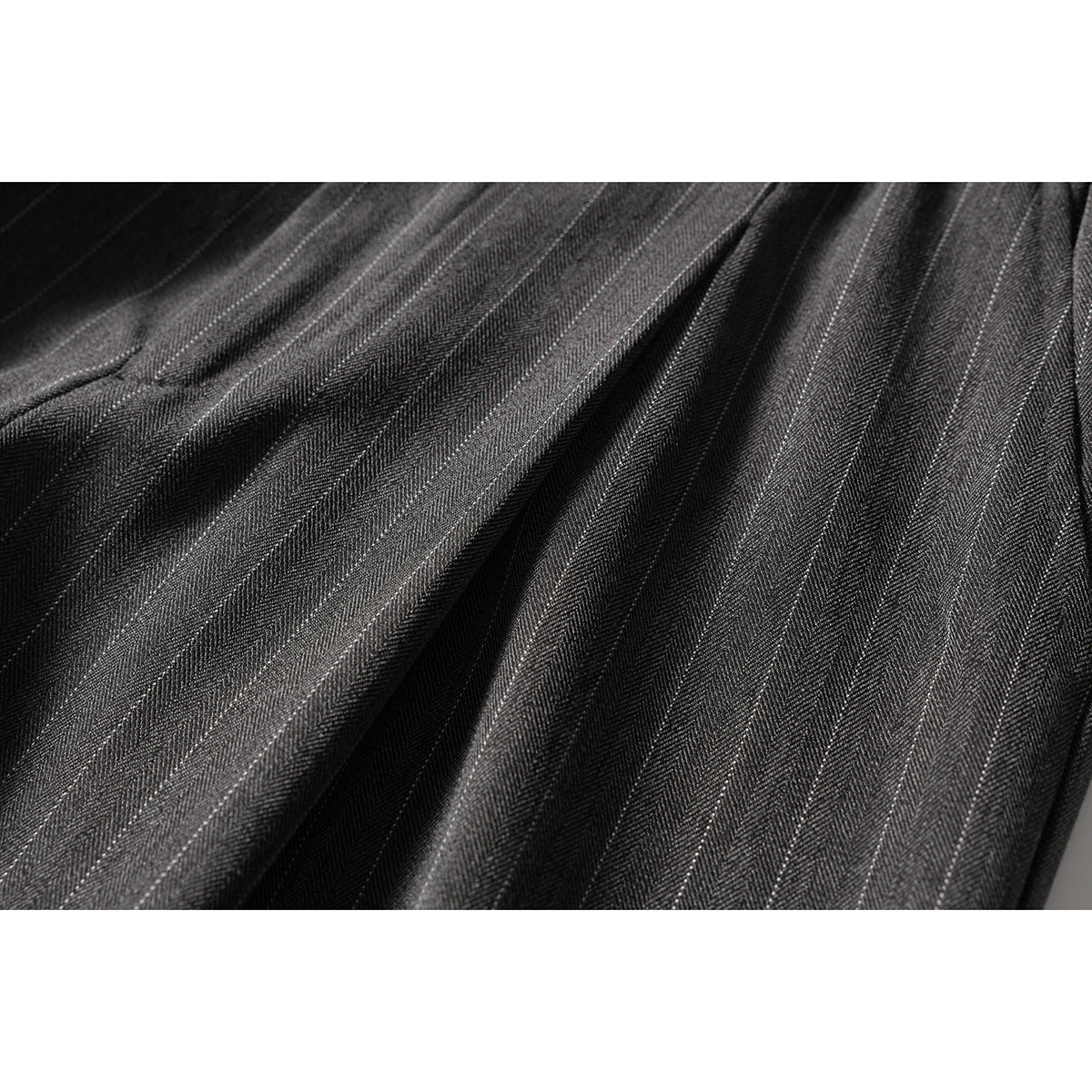 Macro view of charcoal fabric with fine, narrow light pinstripes and visible woven texture.