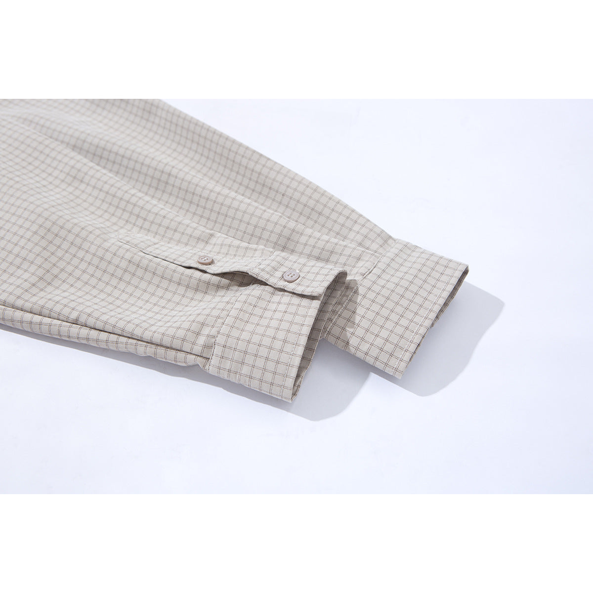 Close-up of a light beige checked shirt sleeve and buttoned cuff.