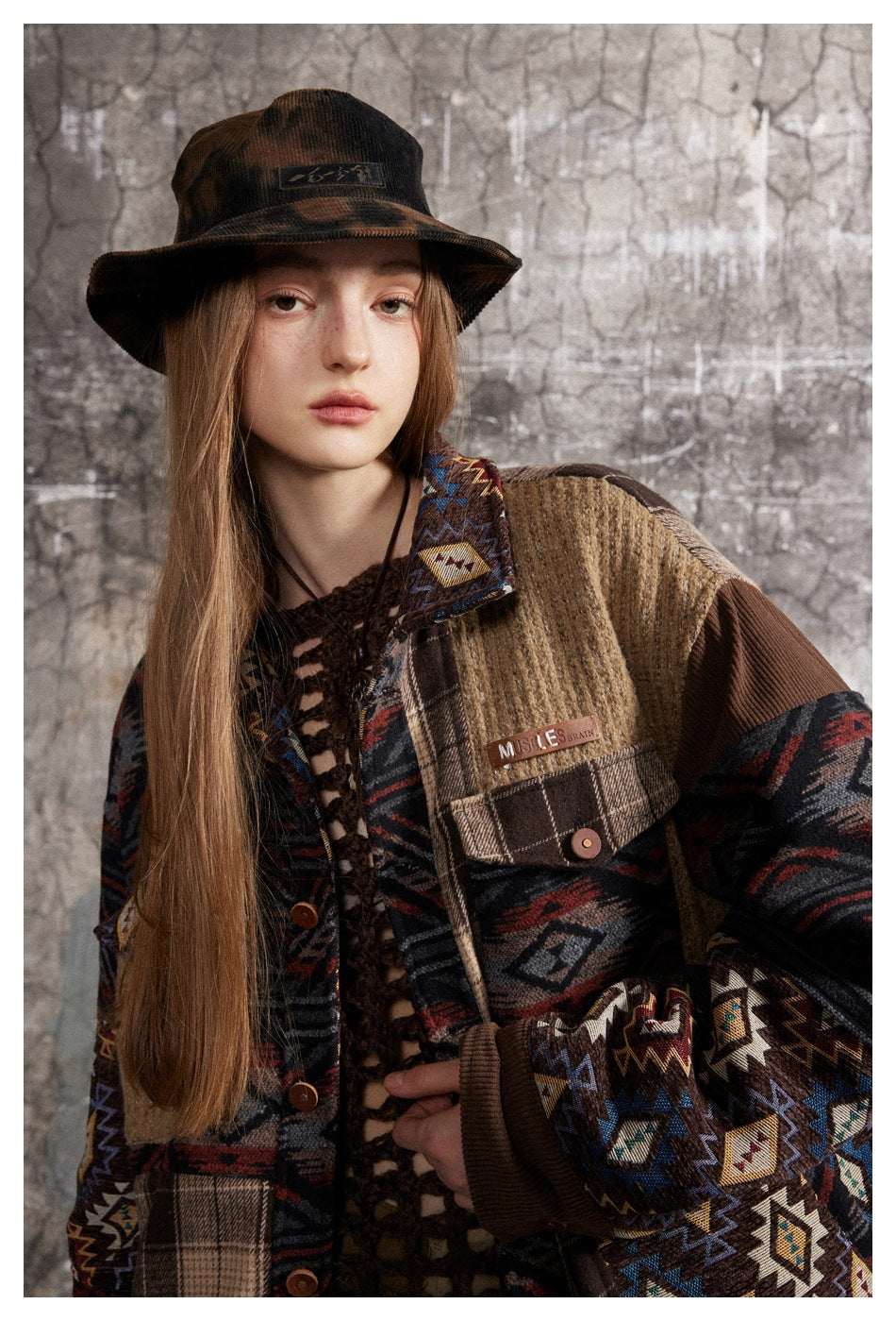 Close-up of the jacket's geometric-print sleeves, plaid pocket, ribbed tan panel, and button closure.