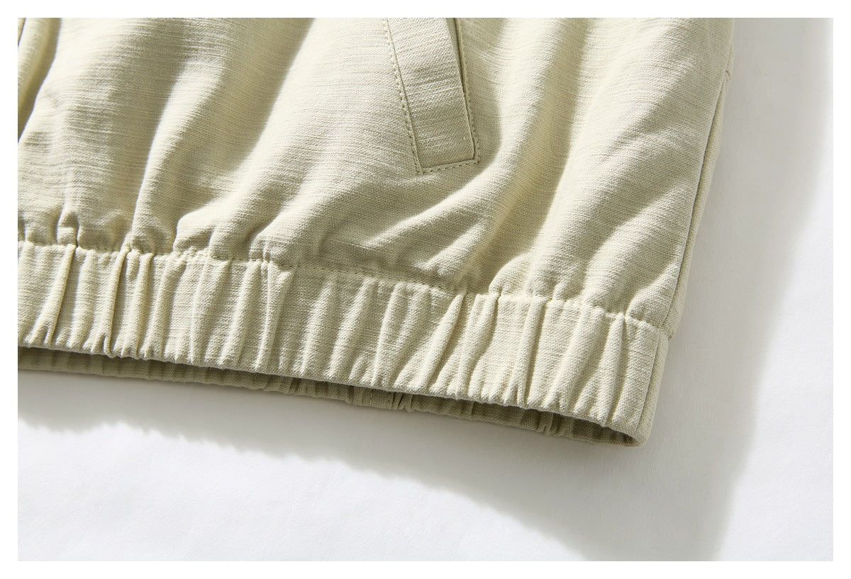 Close-up of the ivory jacket's gathered elastic hem and lower side pocket area.