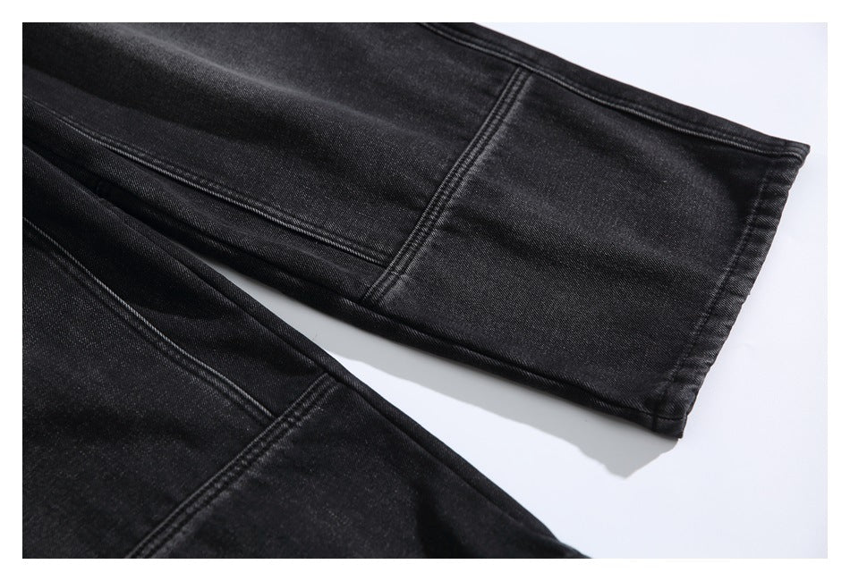 Close-up of the black jeans leg hem and intersecting stitched seams.