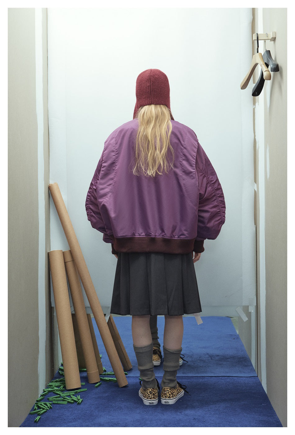 Rear view of a model wearing an oversized purple bomber jacket with dark ribbed hem and cuffs.
