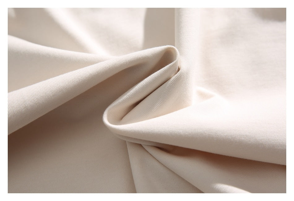 Close-up of ivory T-shirt fabric folded to show its smooth surface and drape.