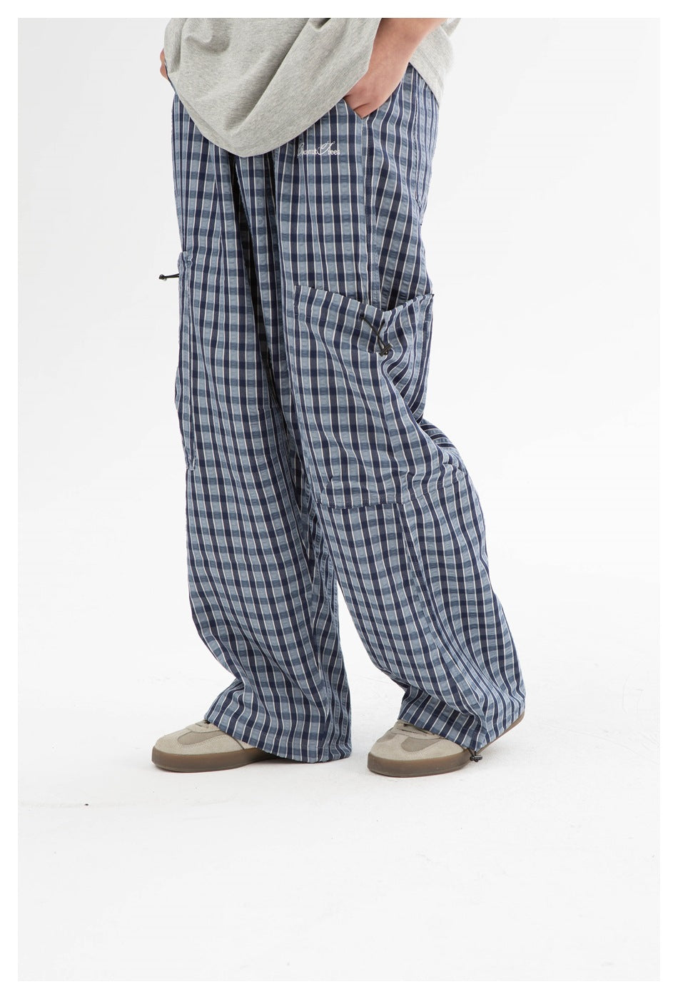 Model wearing loose blue plaid cargo pants with large side pockets and adjustable hems.
