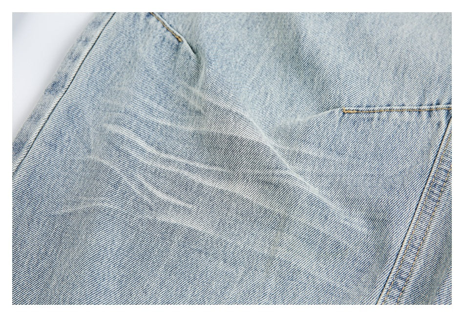 Close-up of light-wash denim with a stitched pocket edge and faded creases.