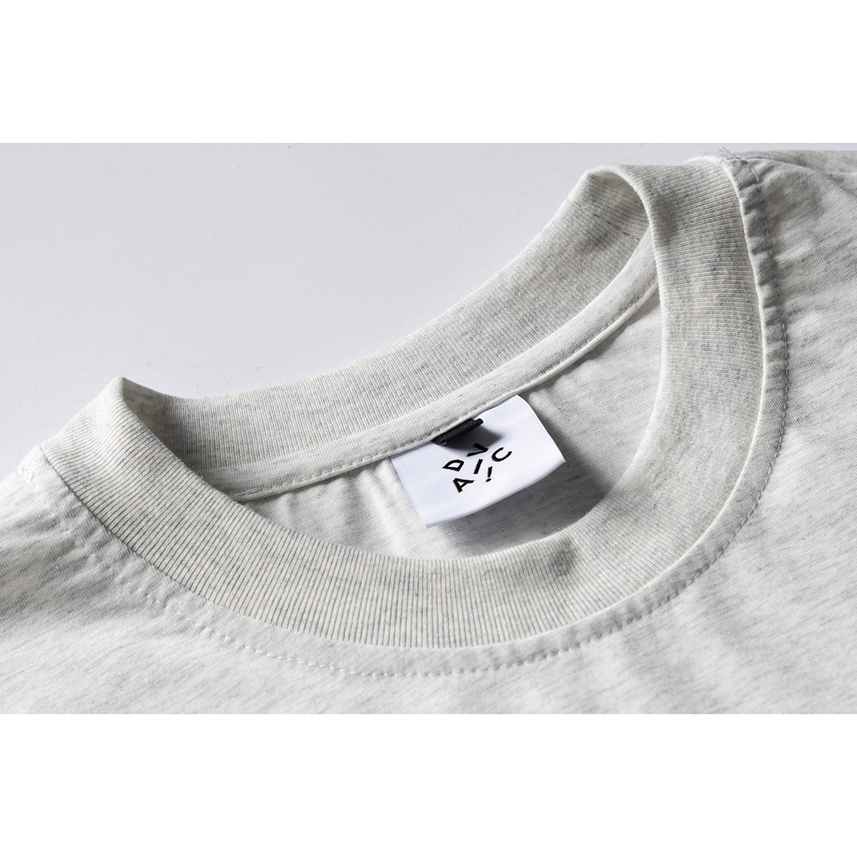 Close-up of a light gray heather T-shirt's ribbed crew neck and small sewn-in label.